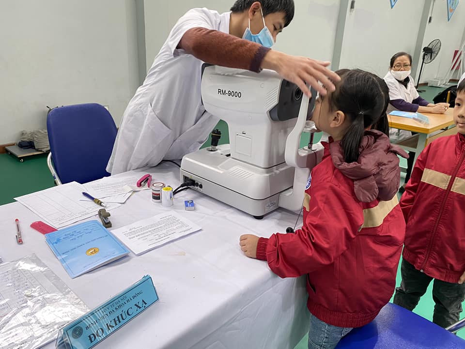 Bác sĩ đang đo thị lực cho học sinh