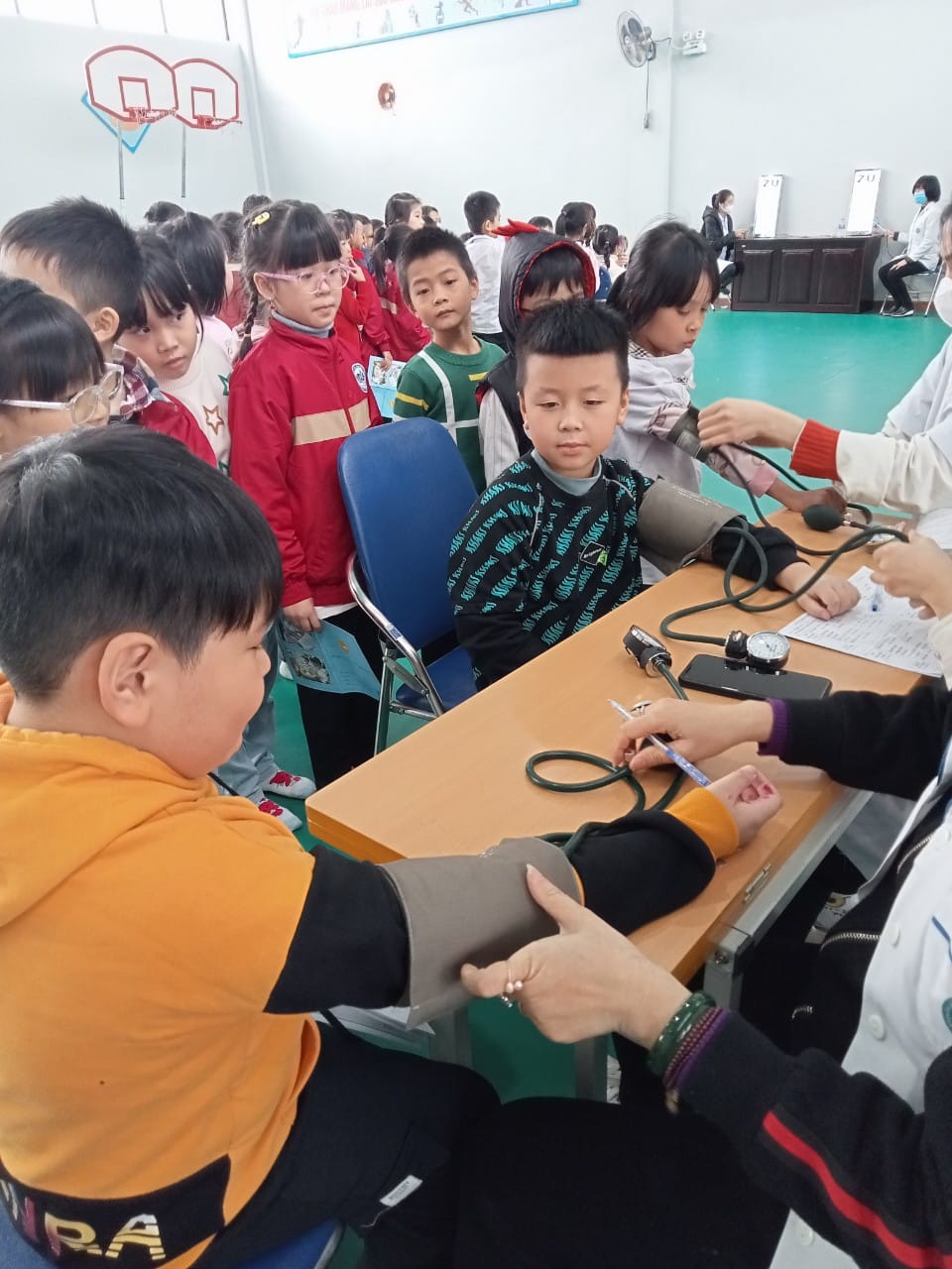 Các bạn học sinh đang được bác sĩ đo huyết áp, nghe tim phổi